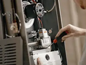 Furnace repair technician inspecting internal components and wiring in Charlotte, NC
