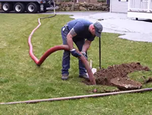 Septic pumping technician servicing a residential septic tank with a vacuum hose in Charlotte, NC