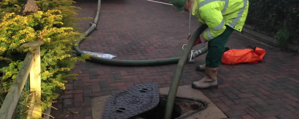 Septic tank cleaning technician servicing a septic tank with a vacuum hose in Charlotte, NC