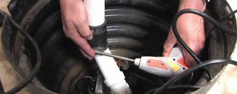 Sump pump installation technician connecting PVC discharge piping in Charlotte, NC